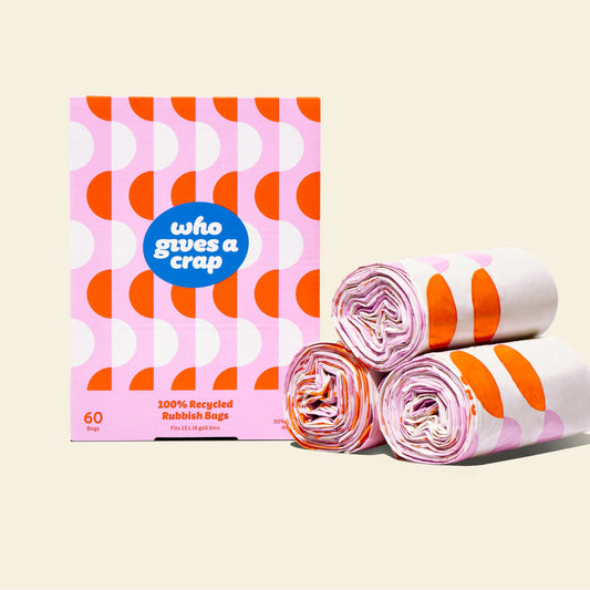 Three rolls and a box of Who Gives a Crap small recycled trashags with pink and orange packaging