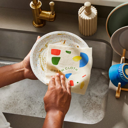 Person cleaning dirty dishes in sink using Who Gives a Crap dream cloth