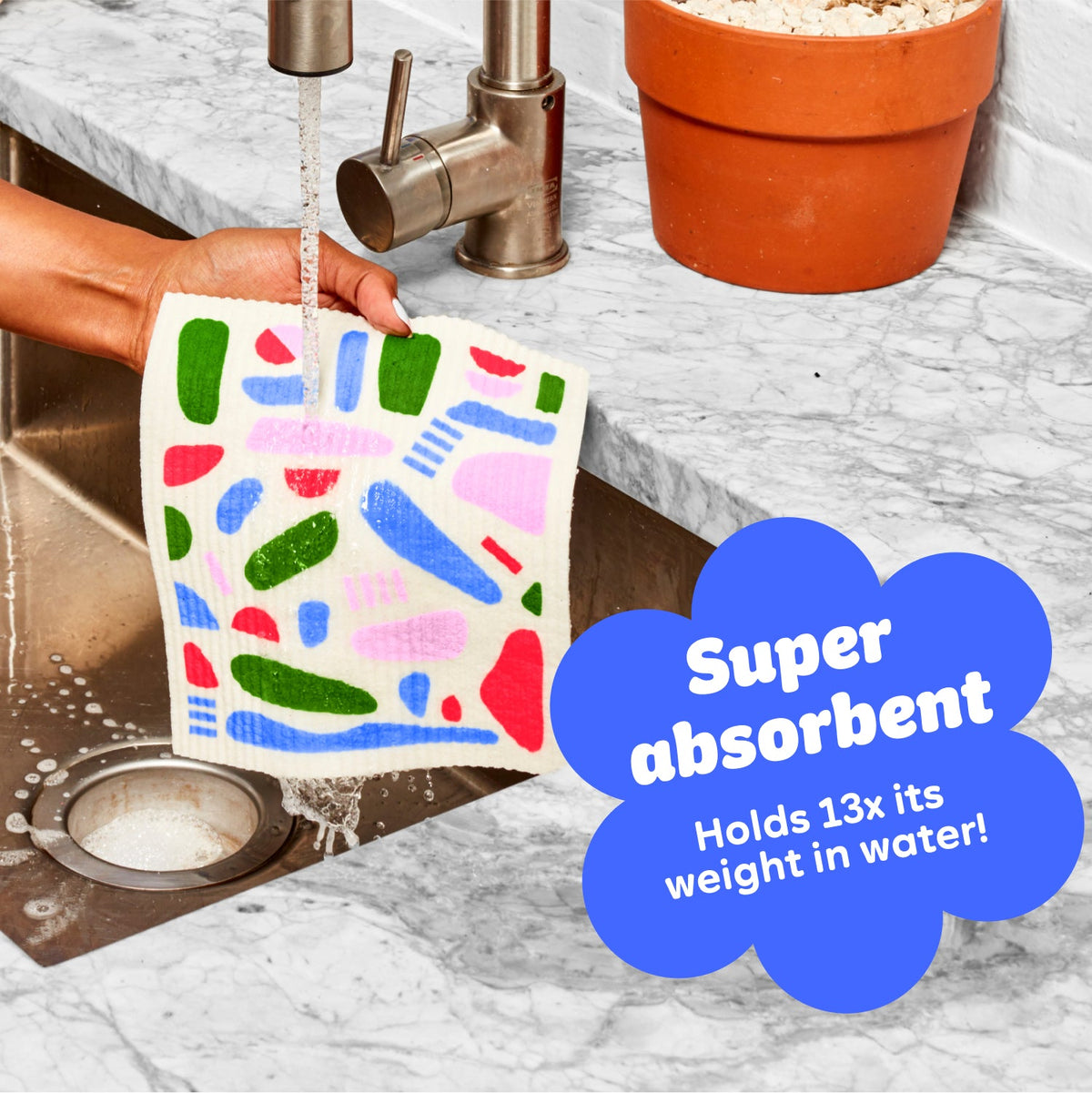 A super absorbent Who Gives A Crap durable Dream Cloth being washed under running water in a kitchen sink, showing how it can hold up to 13 times it’s weight in water.
