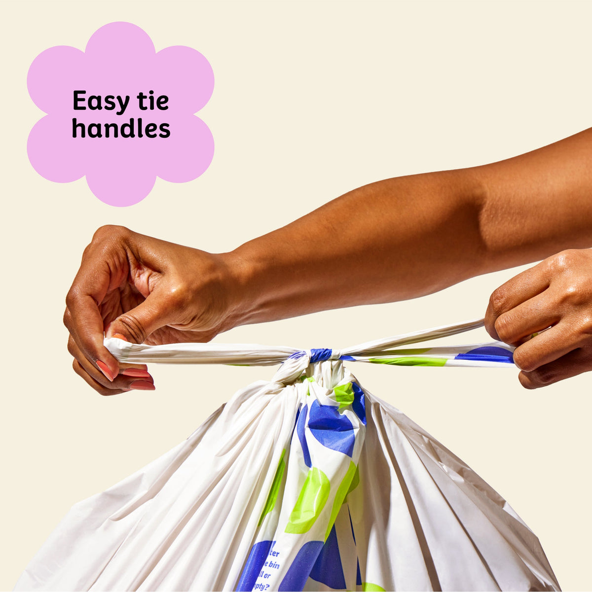 Two hands ties close Who Gives a Crap large recycled trash bag with the easy tie handles.