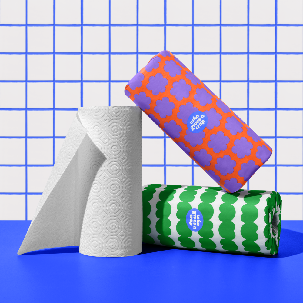 Three rolls of Who Gives a Crap paper towel against blue and white bathroom wall
