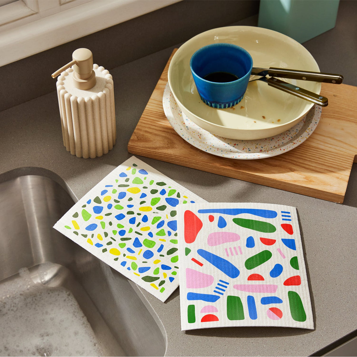 Two Who Gives a Crap colourful dream cloths sitting on kitchen sink next to dirty dishes